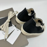 Scarpe slip-on nere eleganti con suola beige, stile minimalista e dettagli moderni.