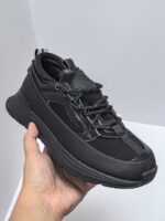 Sneaker nera moderna con suola ammortizzata, sistema di lacci innovativo e design minimalista.