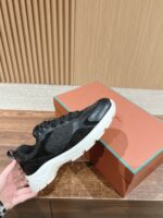 Sneaker nera minimalista con suola bianca su superficie di legno, scatola elegante con dettagli turchesi.