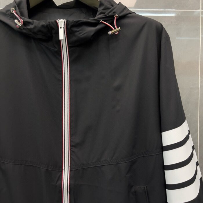 Giacca nera sportiva con cappuccio, zip frontale e dettagli a strisce bianche.