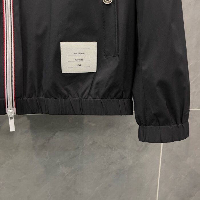 Giacca nera sportiva con zip argentata, logo minimalista e polsini elastici, elegante e comoda.