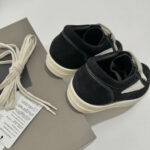 Sneakers nere in suede con lacci cream e suola bianca, stile moderno e versatile.