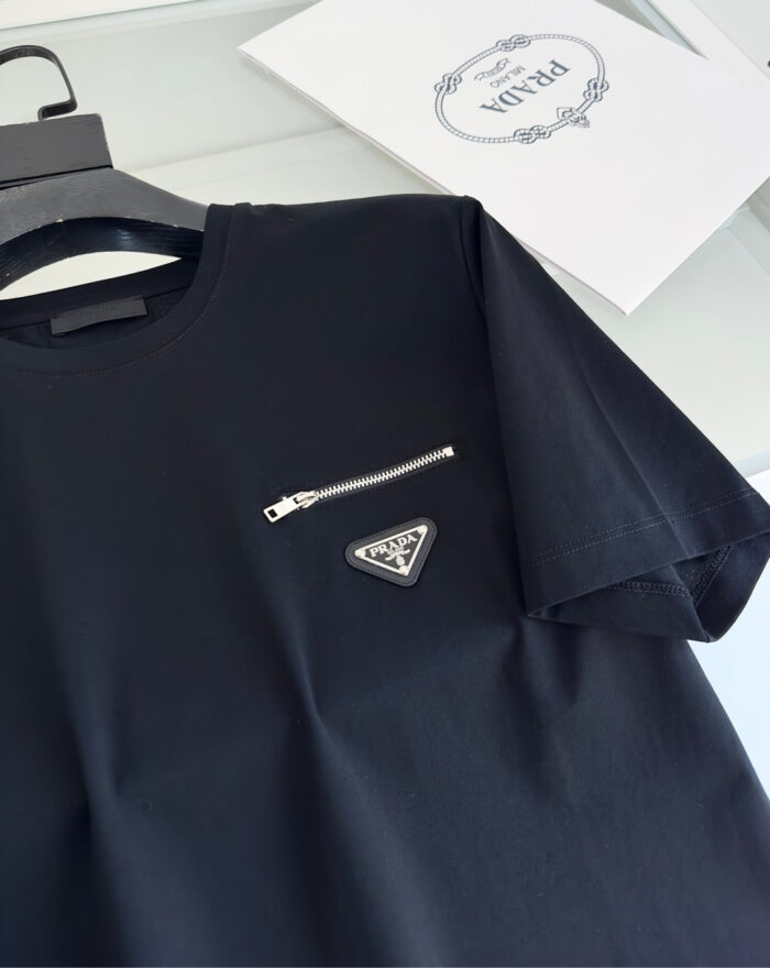 Maglietta nera moderna con tasca a zip e logo triangolare, stile casual ed elegante.