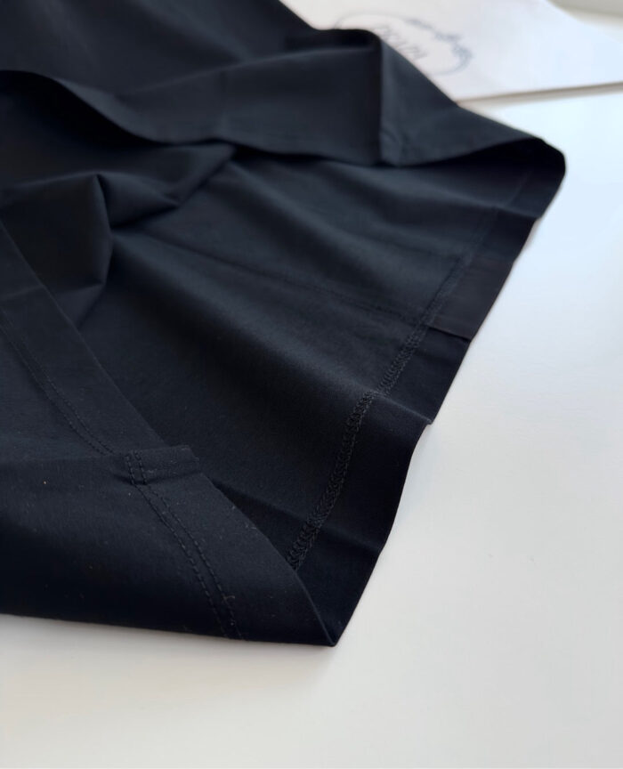 Dettaglio di tessuto nero di alta qualità con cuciture precise e finiture eleganti.