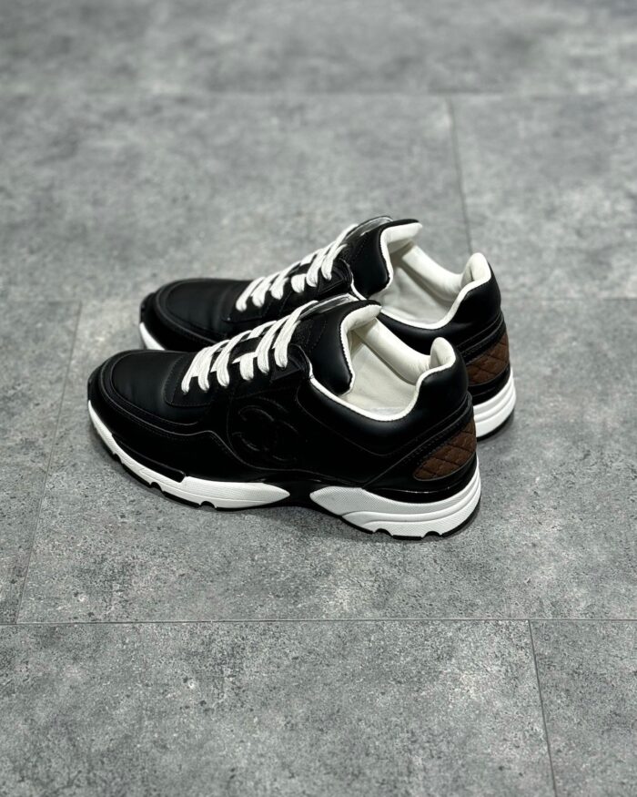 Sneakers nere con dettagli bianchi e marroni, stile moderno, comfort e design versatile.