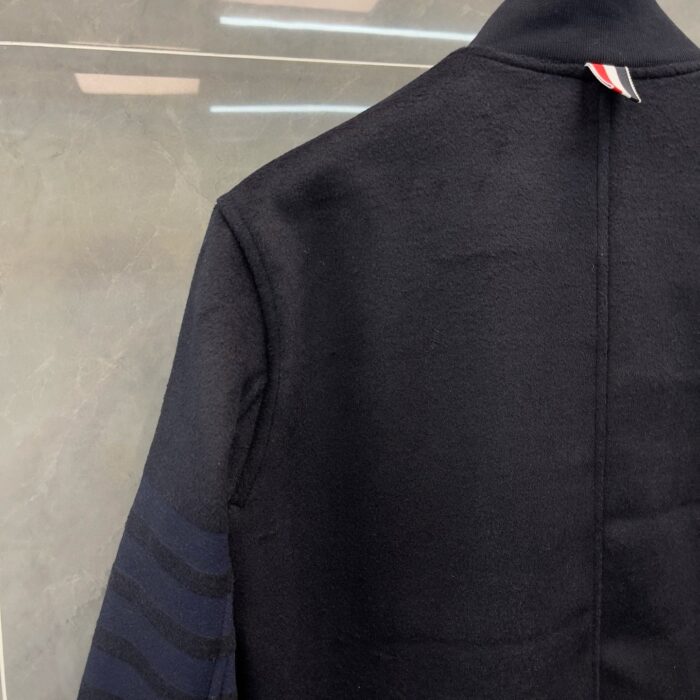 Giaccone nero elegante con maniche a righe e dettagli minimalisti, stile moderno e raffinato.
