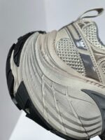 Sneaker sportiva moderna con suola chunky, tomaia in mesh beige e logo Swoosh.