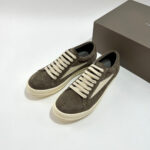 Scarpe sneakers in camoscio marrone scuro con lacci crema, stile elegante e casual.