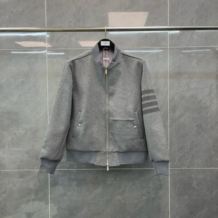 Giacca bomber grigia con zip, polsini a costine e dettagli sportivi sulle maniche.