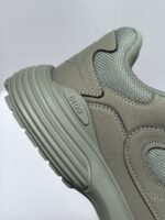 Sneaker grigia moderna con logo di lusso, suola resistente e design urbano elegante.