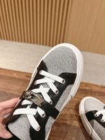 Sneaker grigia sportiva con dettagli neri, cinturino metallizzato e suola bianca, stile casual e moderno.