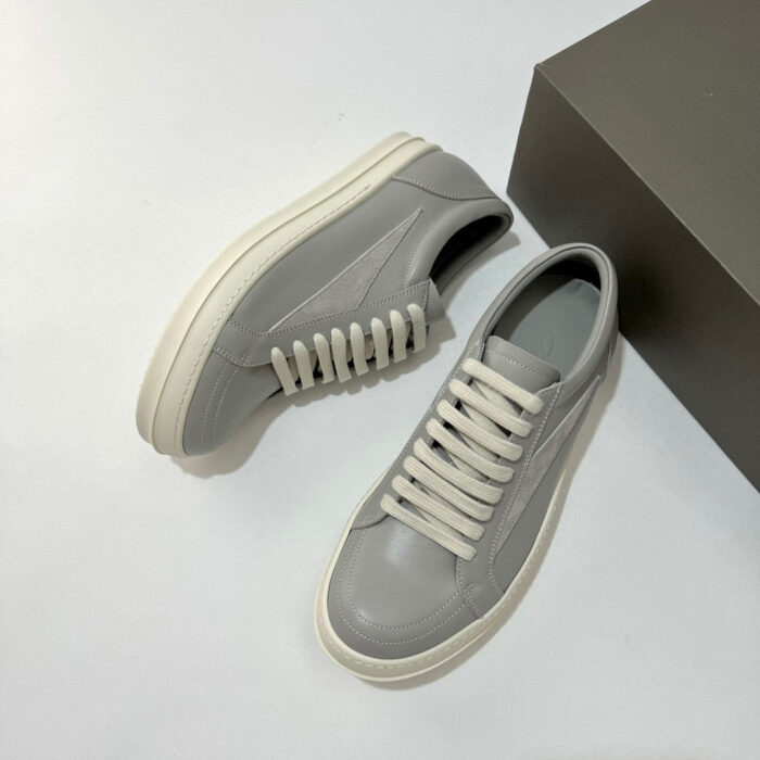 Sneaker grigia moderna con suola spessa e lacci contrastanti, stile casual e urbano.