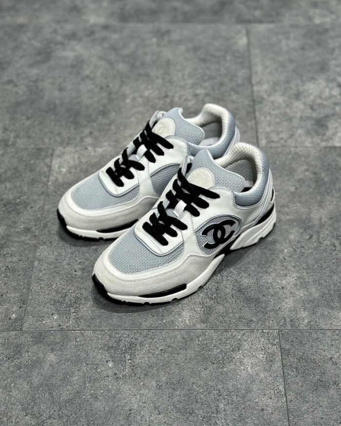 Sneaker di lusso bianche e grigie con emblema nero, stile moderno e comfort urbano.