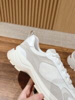 Sneaker bianca e beige moderna, in mesh e suede, su superficie in legno elegante.