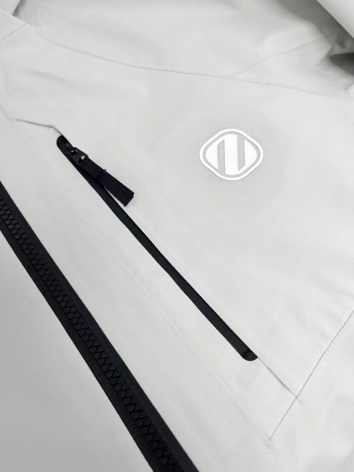 Giacchetto bianco moderno con logo circolare e tasca con zip, stile minimalista e versatile.