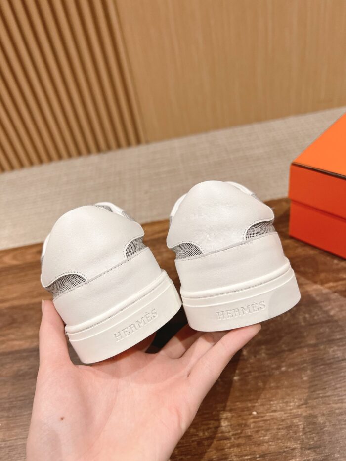 Sneakers bianche di lusso con dettagli eleganti, materiali pregiati e design minimalista.