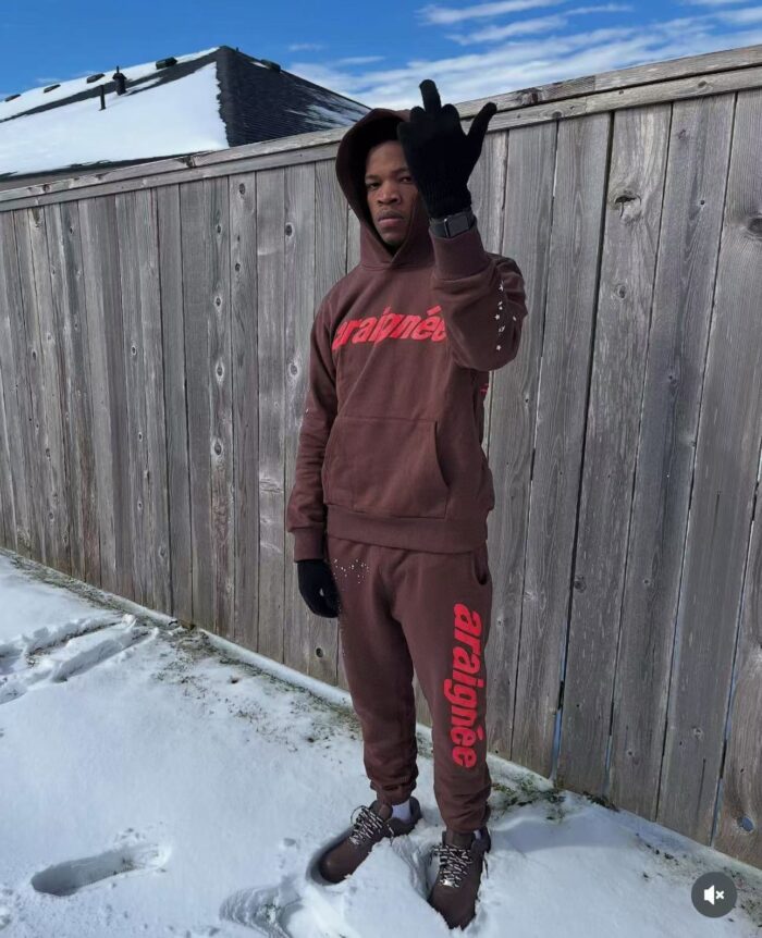 Giovane in streetwear casual in neve, mostra attitude con hoodie e scarpe robuste.