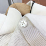 Maglione di alta qualità con collo strutturato e bottone bianco elegante.