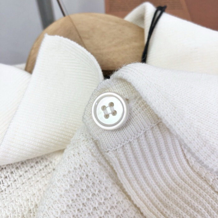 Maglione di alta qualità con collo strutturato e bottone bianco elegante.