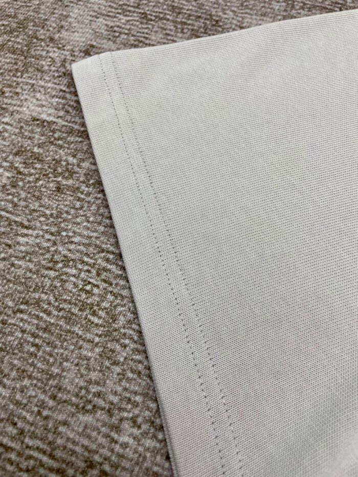 Tessuto di cotone beige con cuciture di alta qualità e dettagli raffinati.