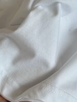 Tessuto di cotone bianco morbido con cuciture precise e superficie liscia e brillante.