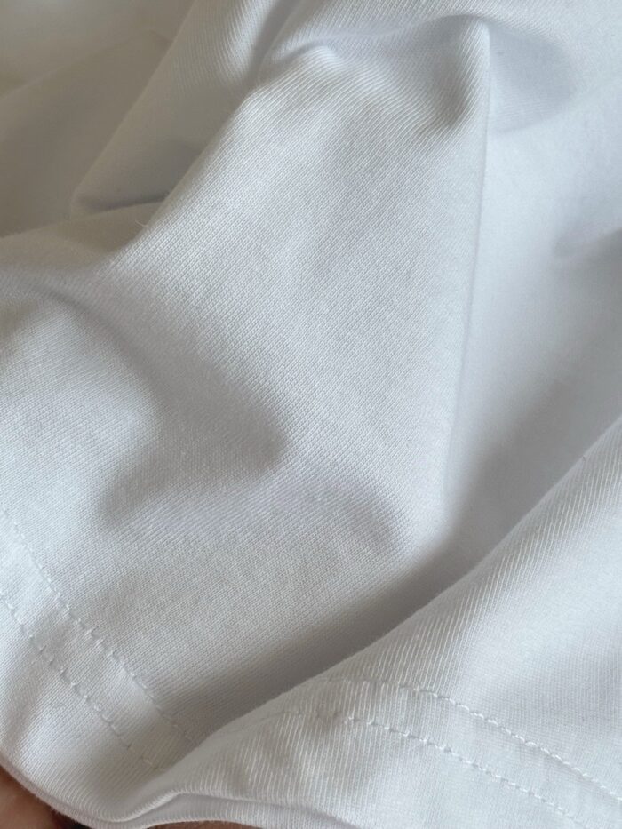 Tessuto di cotone bianco morbido con cuciture precise e superficie liscia e brillante.