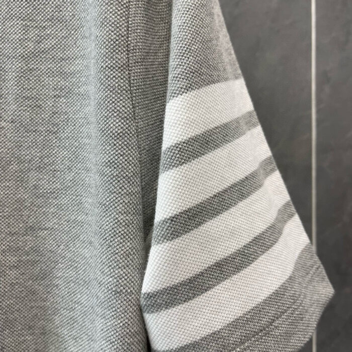 Manica in tessuto grigio morbido con sottili righe orizzontali, stile casual ed elegante.