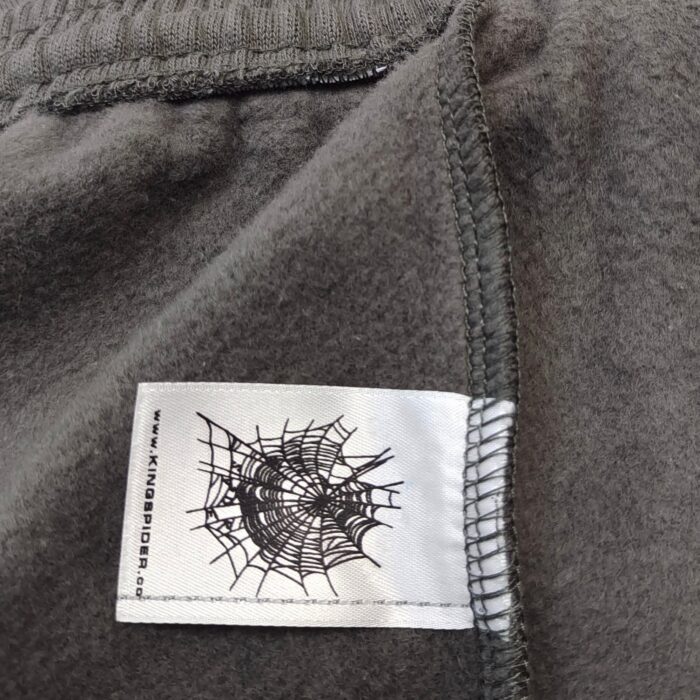 Maglione in pile grigio con etichetta ragnatela nera, stile casual e outdoor.