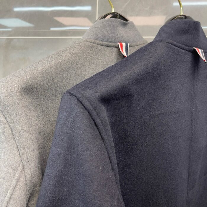 Giacche eleganti a collo alto in tessuto morbido grigio e navy, dettagli raffinati e stile moderno.
