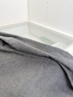 Tela grigia minimalista su superficie in vetro, atmosfera di eleganza e tranquillità.