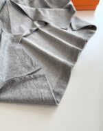 Tessuto grigio morbido con pieghe eleganti, sfondo con scatola arancione vibrante.