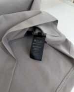Maglione grigio morbido con etichetta nera moderna, tessuto lucido e texture elegante.