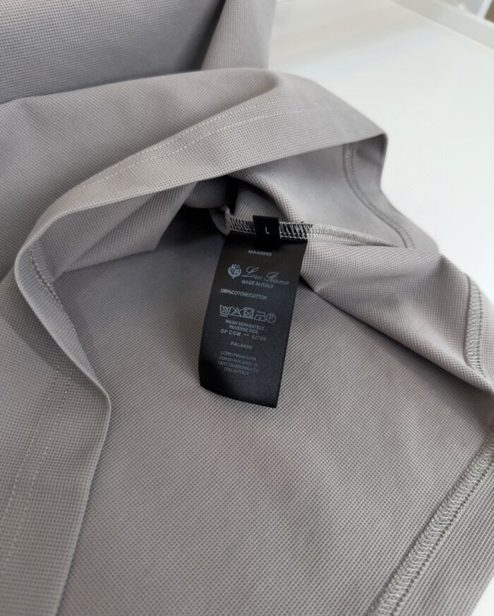 Maglione grigio morbido con etichetta nera moderna, tessuto lucido e texture elegante.