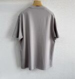 T-shirt grigia oversize in cotone, stile casual ed elegante, su appendiabiti di legno.