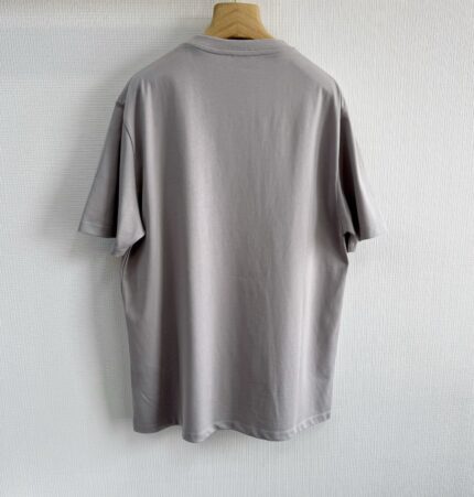 T-shirt grigia oversize in cotone, stile casual ed elegante, su appendiabiti di legno.