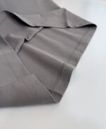 Tessuto grigio morbido e leggero con cuciture eleganti, ideale per abbigliamento moderno e versatile.