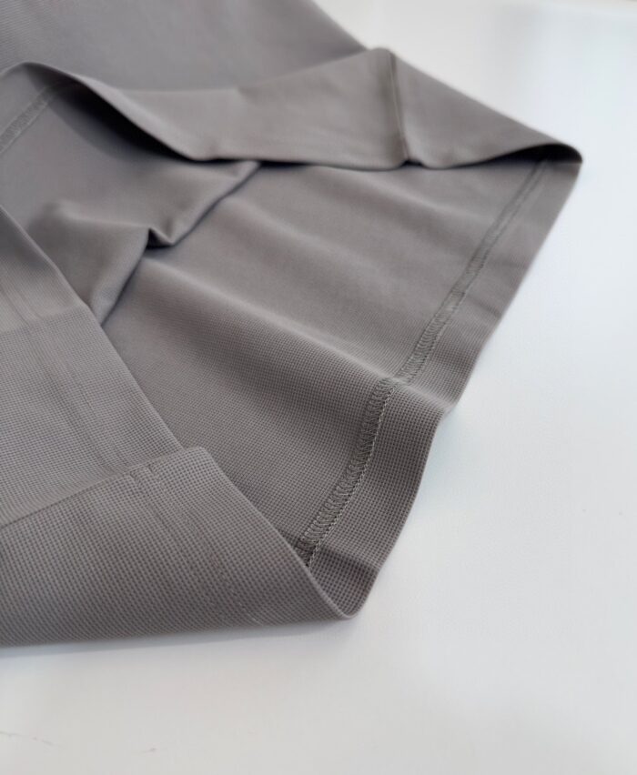 Tessuto grigio morbido e leggero con cuciture eleganti, ideale per abbigliamento moderno e versatile.