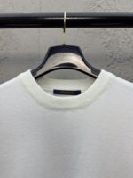 Maglione bianco semplice su appendiabiti moderno, ideale per stile casual e raffinato.
