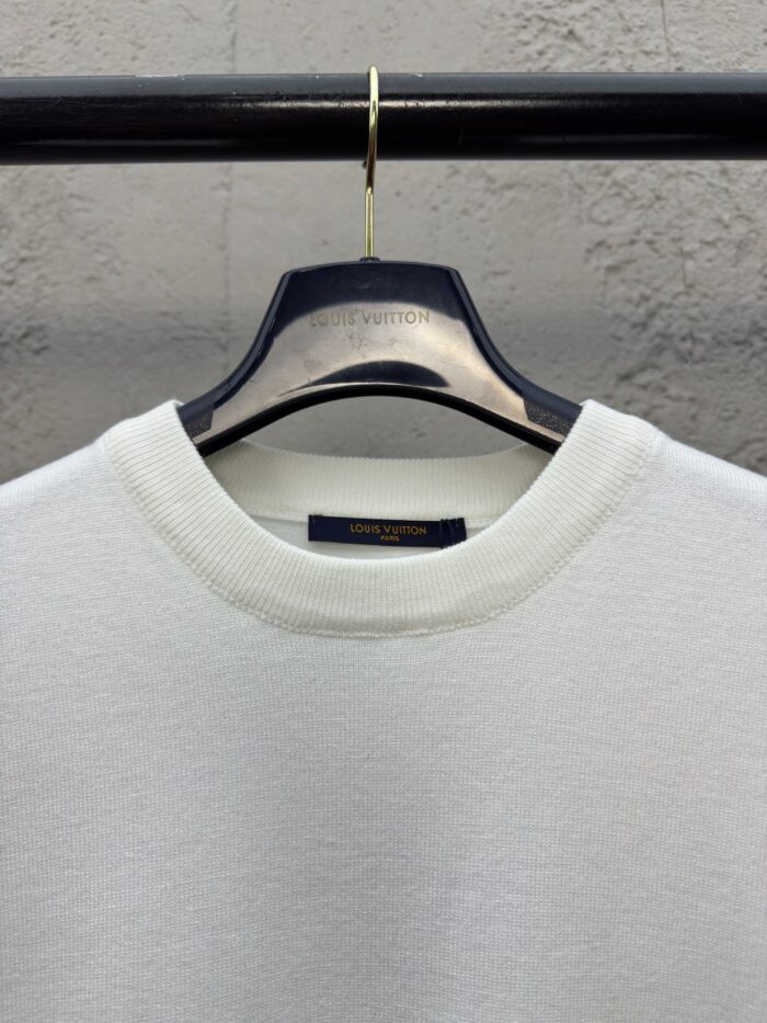 Maglione bianco semplice su appendiabiti moderno, ideale per stile casual e raffinato.