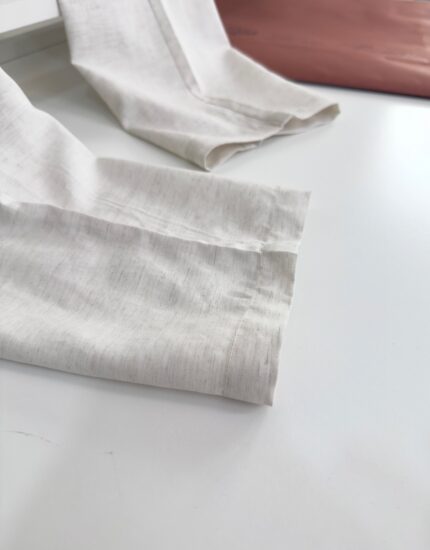 Maniche in lino leggero con polsini cuciti, contrasto elegante con dettaglio in pelle morbida.