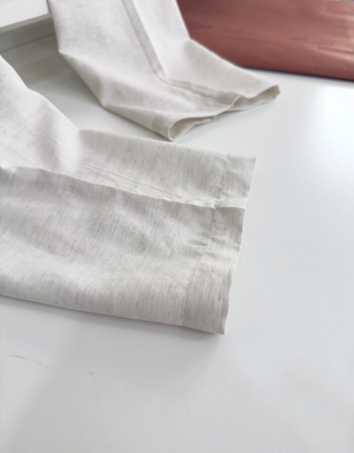 Maniche in lino leggero con polsini cuciti, contrasto elegante con dettaglio in pelle morbida.