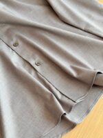 Blusa grigia elegante con bottoni metallici e tessuto morbido, perfetta per occasioni raffinate e casual.