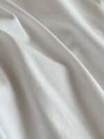 Tessuto bianco morbido con pieghe leggere e riflessi delicati, ideale per arredamento e abbigliamento.