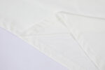 Tessuto bianco elegante con pieghe precise e cuciture pulite, ideale per abbigliamento o décor.