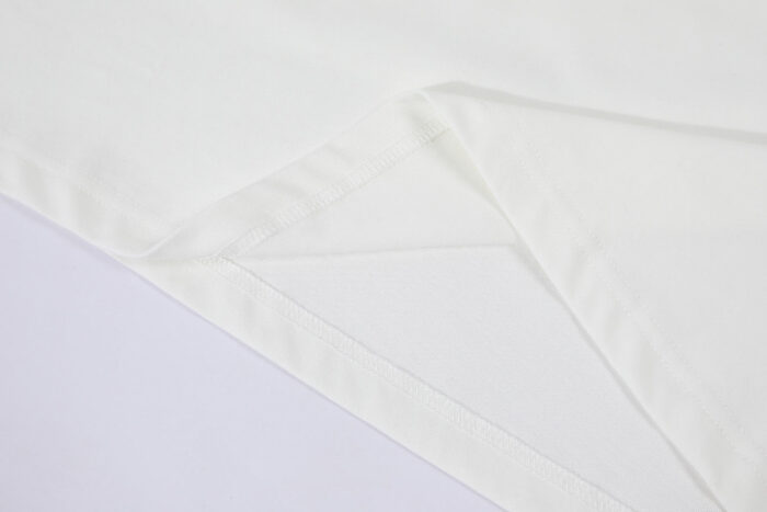 Tessuto bianco elegante con pieghe precise e cuciture pulite, ideale per abbigliamento o décor.
