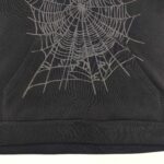 Felpa nera con design di ragnatela dettagliata e tasca anteriore, stile goth e alternativo.
