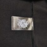 Etichetta con ragnatela bianca su sfondo nero, stile alternativo e dettagli curati.
