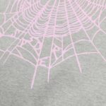 Web a ragnatela rosa pastello su tessuto grigio, stile casual e originale.