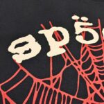 Maglietta nera con testo vintage e ragnatela rossa, stile streetwear alternativo e horror.