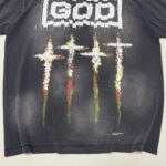 T-shirt nero streetwear con croci colorate e parola GOD effetto glitch e stile distressed.